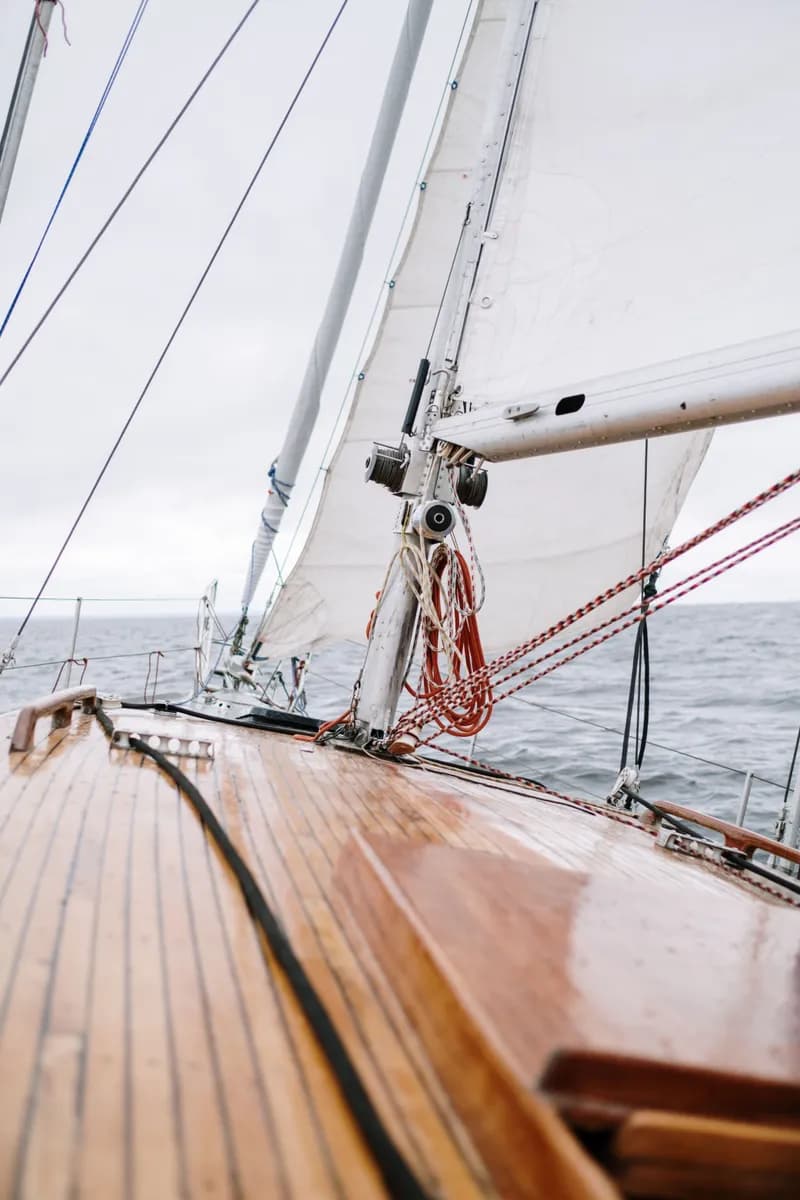 Imagen de ejemplo de BookNoFees: cubierta de madera de un velero con cuerdas y una vela blanca