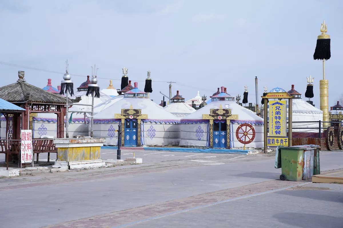 Imagen de ejemplo de BookNoFees: yurtas redondas con puertas decoradas a lo largo de un camino pavimentado