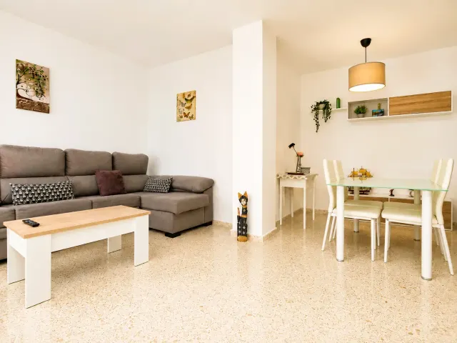 BookNoFees: alquiler vacacional en Jerez De La Frontera – Salón con sofá gris y zona de comedor con mesa de cristal