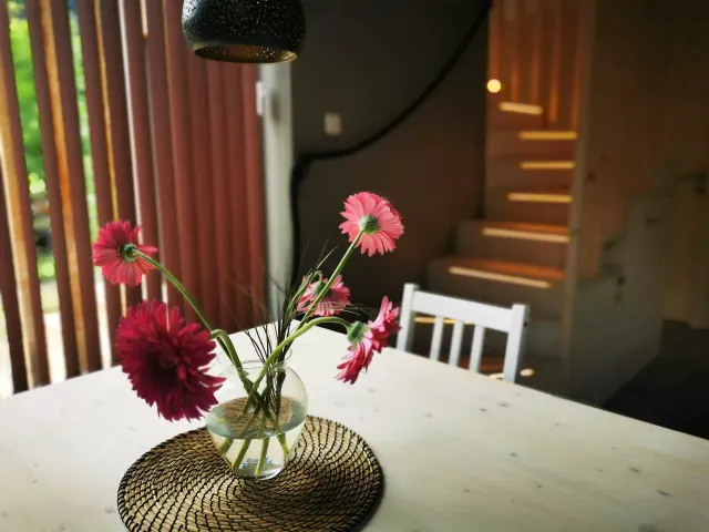 BookNoFees: alquiler vacacional en Hieflau, Estiria, Austria – Comedor con una mesa blanca, un jarrón con flores rosas y una escalera de madera