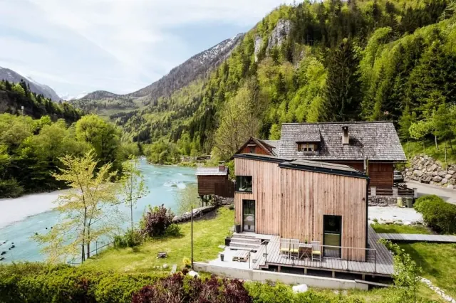 BookNoFees: alquiler vacacional en Hieflau – Vista exterior de una casa de vacaciones de madera con el río y la montaña como telón de fondo