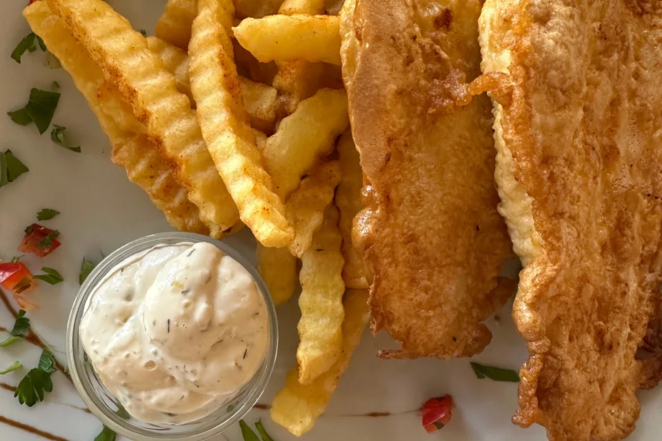 BookNoFees: Foto de ejemplo: Filetes de pescado rebozados con patatas fritas onduladas y un cuenco pequeño de salsa
