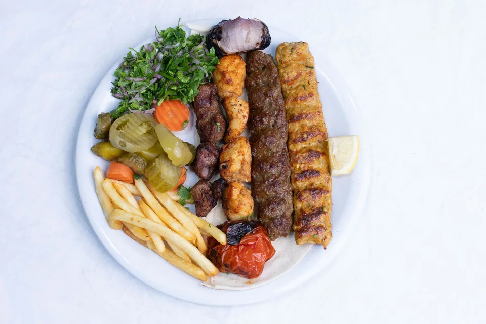 BookNoFees: Foto de ejemplo: Brochetas a la parrilla servidas con ensalada y patatas fritas